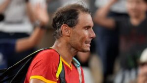 "Rafael Nadal, vestido con ropa de tenis, saluda emocionado al público, con una raqueta en la mano y la cabeza baja, en un gesto de despedida tras anunciar su retiro del tenis profesional."